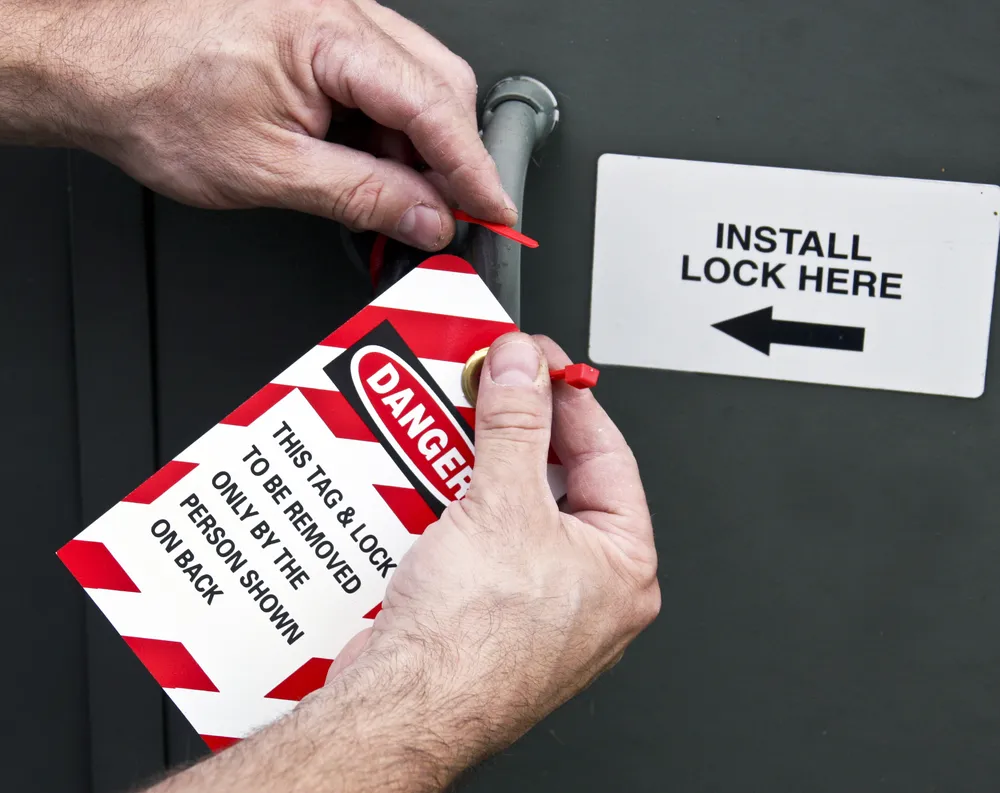 Worker attaching danger lockout tag to machinery
